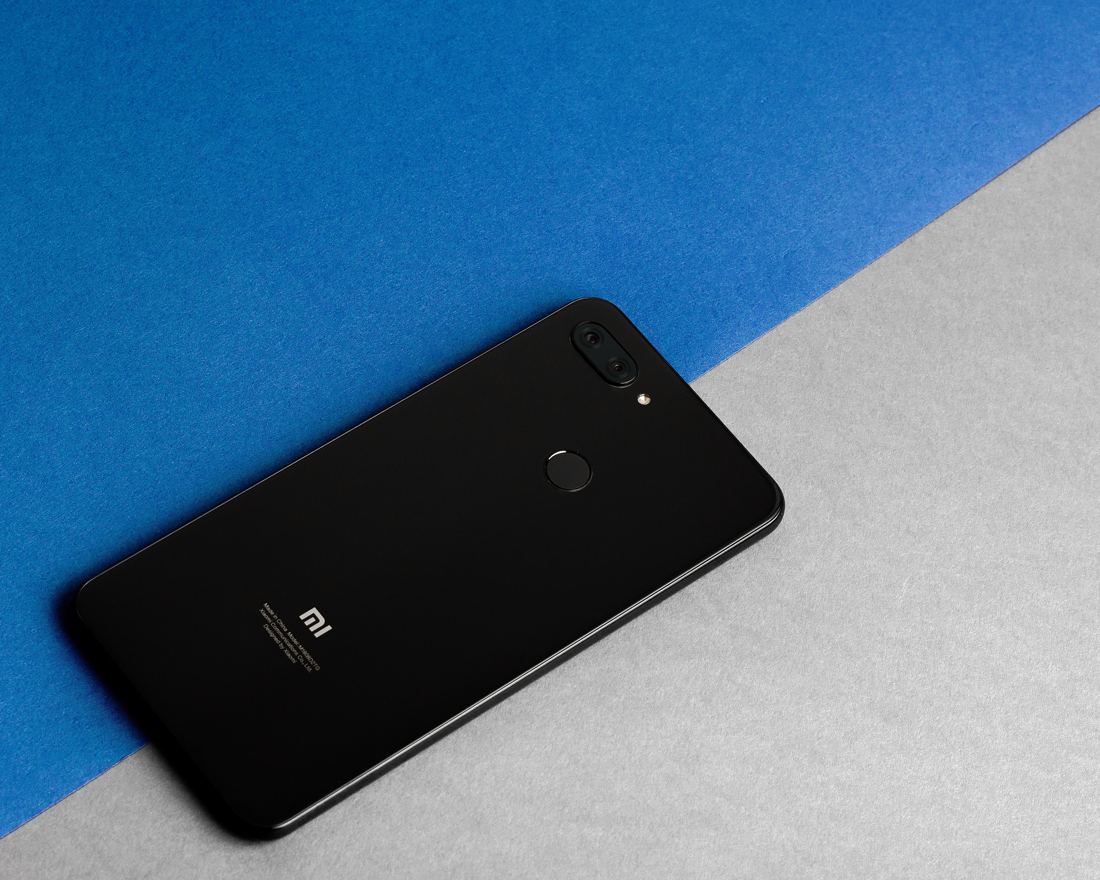 Smartphone Xiaomi visto de trás, sobre fundo azul e cinza